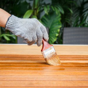imbianchino che applica Impregnante o vernice per legno esterno su asse in legno