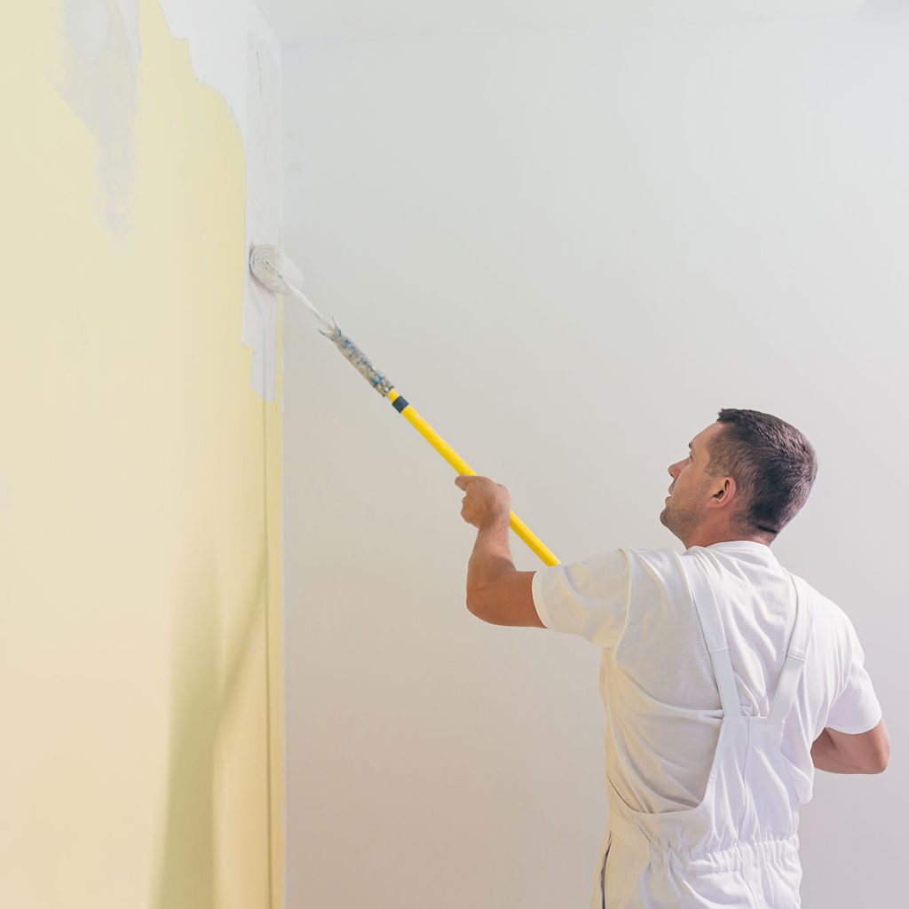 Imbianchino che applica una pittura lavabile o traspirante gialla